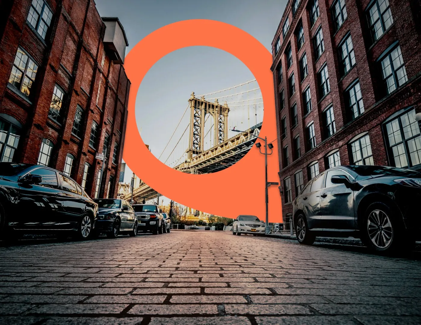 The Alleyoop pin mark framing the Manhattan Bridge from a cobblestone street in DUMBO, Brooklyn